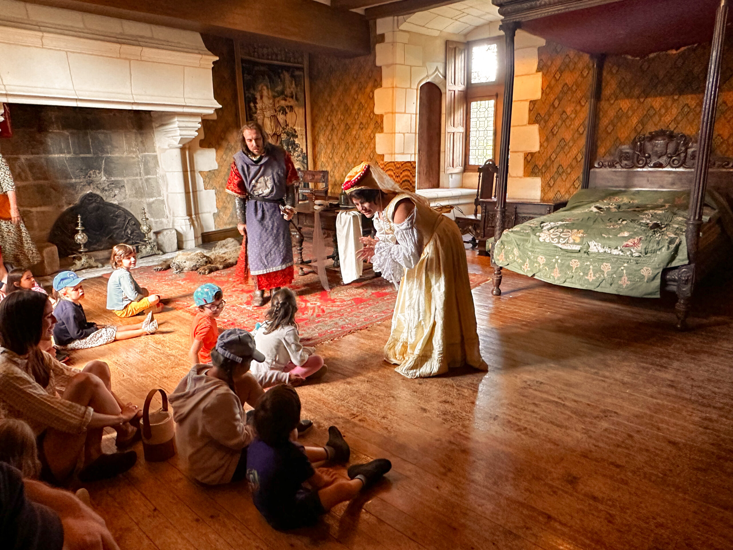 Photo de deux médiateurs déguisés en princesse et chevalier jouant une saynète devant des enfants dans une pièce du château